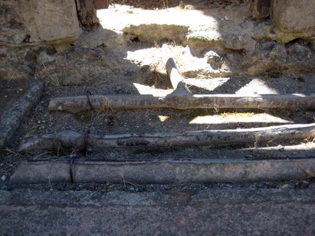 V.9 Herculaneum, June 2011. Detail of lead pipes in pavement outside doorway, looking east. Photo courtesy of Sera Baker.
